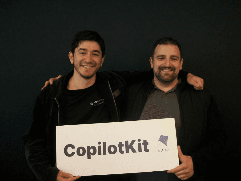 CopilotKit co-founders Uli Barkai and Atai Barkai holding a CopilotKit sign